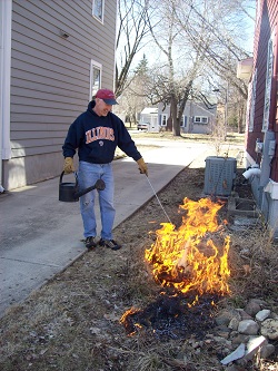 man supervising prescribed burn of native landscape beside his home