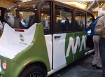 green and white driverless car on a convention floor