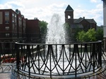 fountain behind ornate railing church in background
