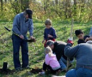 Tree Planting in a Park is a Good First Sustainability Project children and an adult planting tree