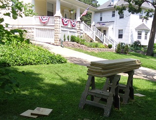 sawhorses and lumber on lawn as housing renovation proceeds