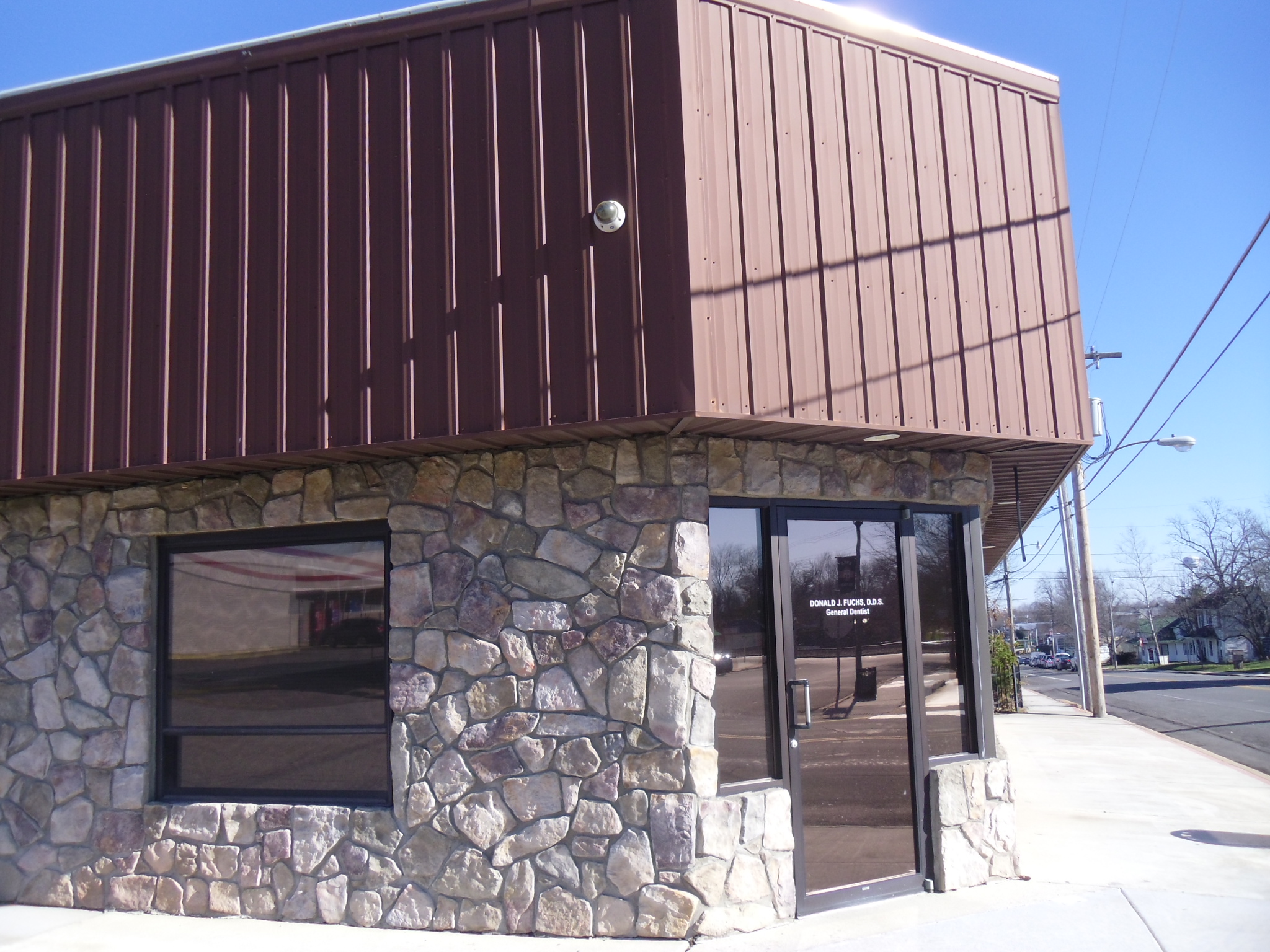building with first story made of local rock and second story aluminum awning once popular
