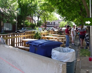 Picnic tables and music take over on-street parking spaces for a day pop-up event space including picnic tables on parking spots