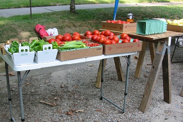 peppers, tomatoes and squash at folder table at farmers market